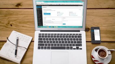 A laptop, a mobile, a notebook, and a cup of coffee, which are helpful to start blogging